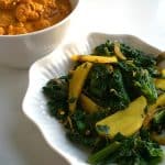 A bowl of Aloo Palak (Sauteed Spinach with Potatoes) served with a side of Chicken Curry.
