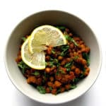 A bowl of Kala Chana Masala, also known as Sukhe Kale Chane, garnished with fresh cilantro and lemon wedges.
