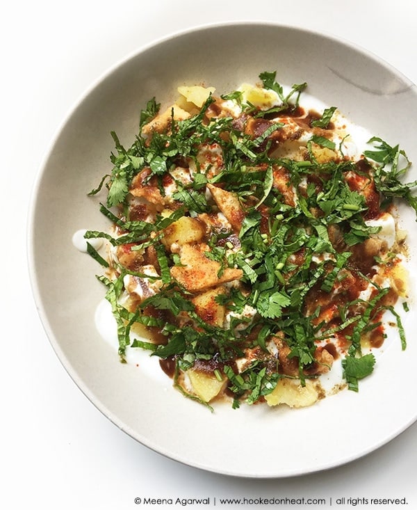 A bowl of Dahi Papdi Chaat garnished with chutneys and fresh cilantro.