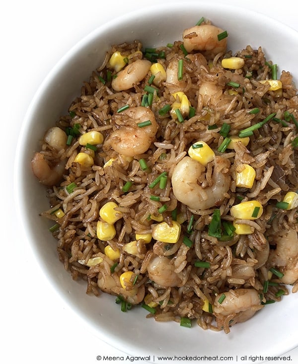 A bowl of Corn Fried Rice with Shrimp garnished with fresh chives.