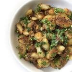 A bowl of Dry Aloo Sabzi (Sukhe Aloo) garnished with fresh cilantro.