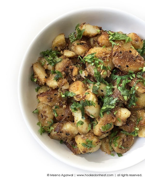 A bowl of Dry Aloo Sabzi (Sukhe Aloo) garnished with fresh cilantro.