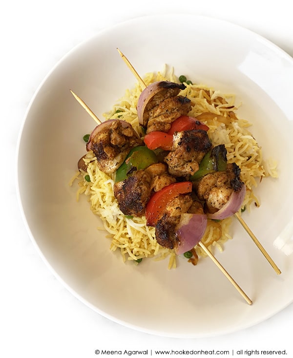 A platter of Turkey Tikka Skewers served over a bed of spiced  rice