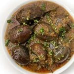 A bowl of Baingan Masala or Aubergine Curry garnished with fresh cilantro.