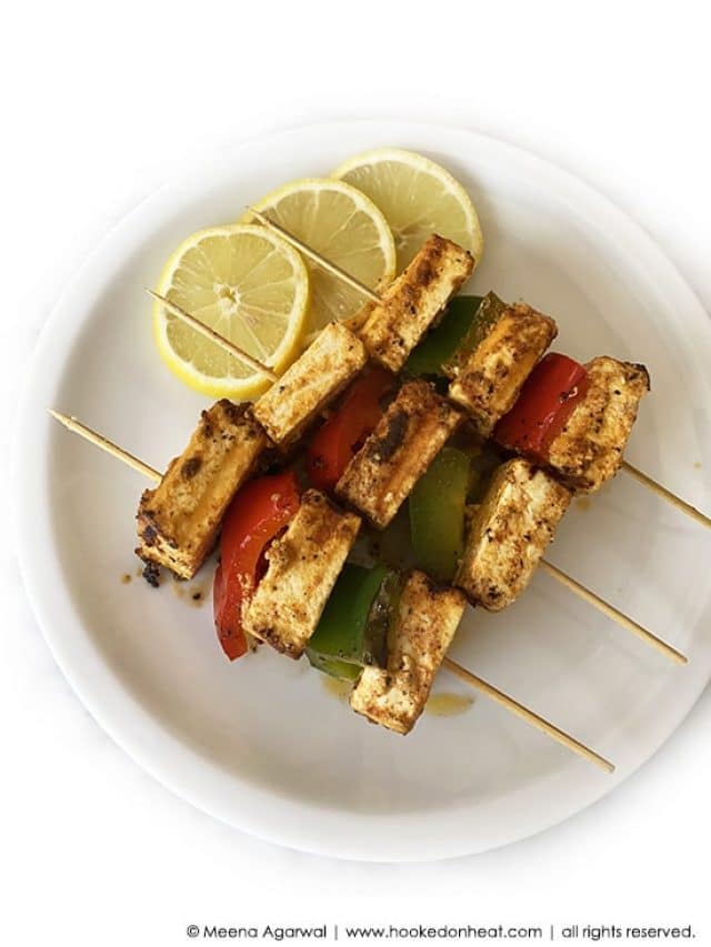 A platter of Paneer Tikka Shashlik skewered with onions and peppers.