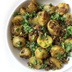 A bowl of Aloo Masala garnished with fresh cilantro leaves.