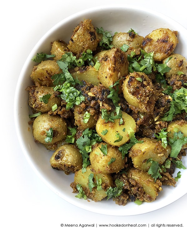 A bowl of Aloo Masala garnished with fresh cilantro leaves.