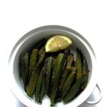 A bowl of Bharwaan Bhindi (Spice Stuffed Okra) garnished with a lemon wedge