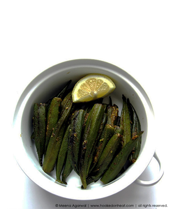 A bowl of Bharwaan Bhindi (Spice Stuffed Okra) garnished with a lemon wedge