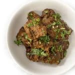 A bowl of Bhuna Chicken, also known as Chicken Bhuna Masala, garnished with fresh cilantro leaves.