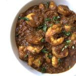 A bowl of Malaysian Tamarind Shrimp, also known as Asam Prawns, garnished with fresh cilantro leaves.