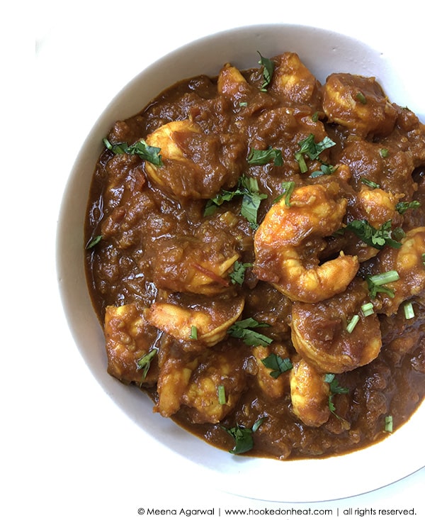 A bowl of Malaysian Tamarind Shrimp, also known as Asam Prawns, garnished with fresh cilantro leaves.