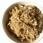 A white bowl of Sooji Halwa, also known as Semolina Halwa, garnished with finely chopped almonds.