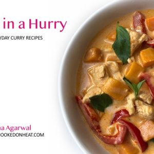 A bowl of creamy curry with chicken, red bell peppers, orange chunks, and fresh basil leaves. Text reads “Curries in a Hurry: Simple Everyday Curry Recipes” by Meena Agarwal, creator of hookedonheat.com.